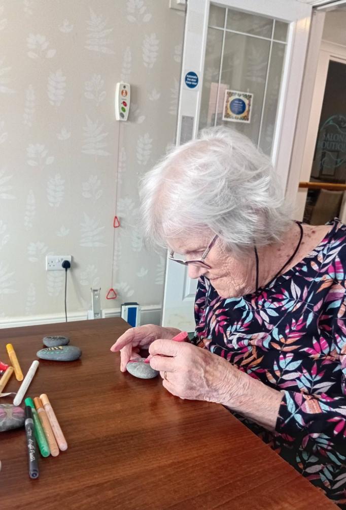 older lady sat down painting on a stone for arts and crafts