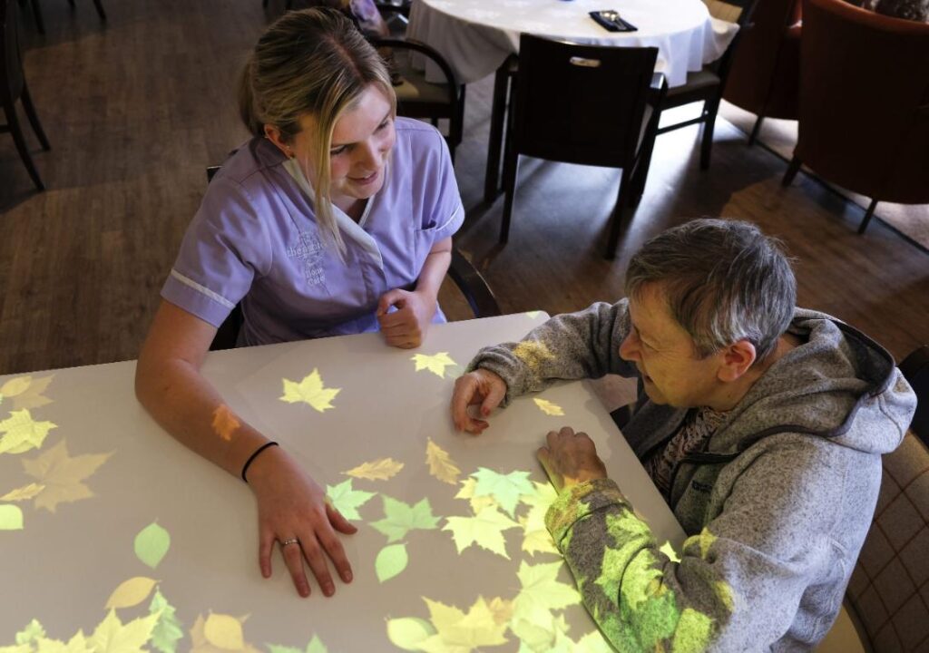 Resident and staff member enjoy sensory activity with leaf projections