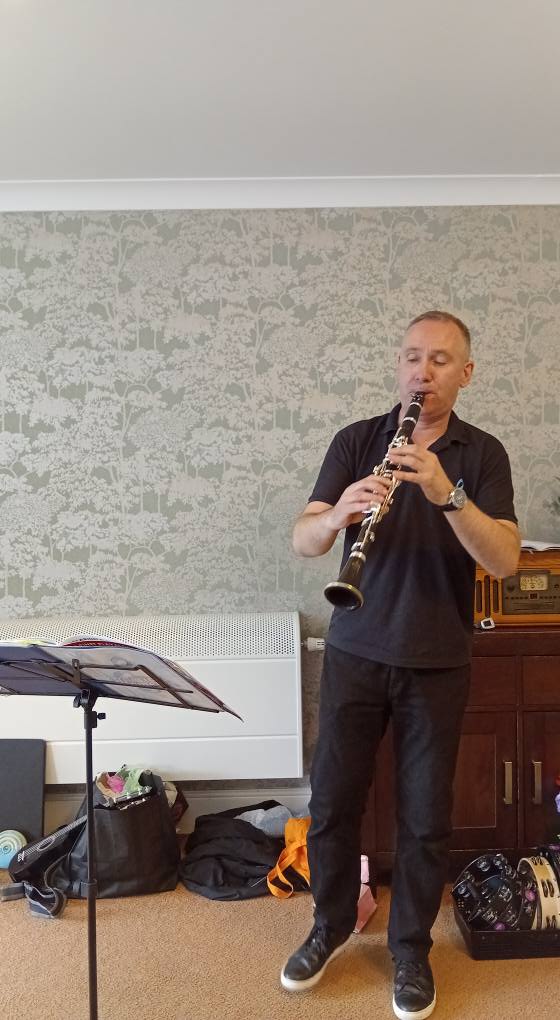 a man standing playing a clarinet