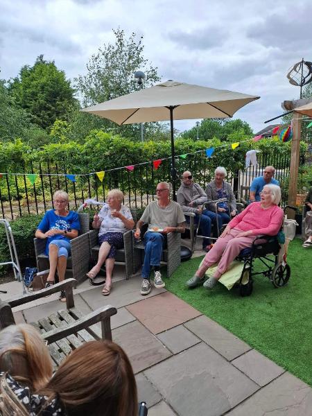 Elderly people sitting together in a green garden, enjoying the outdoors.