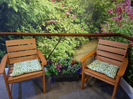 two wooden chairs with green cushions on and a pot of flowers