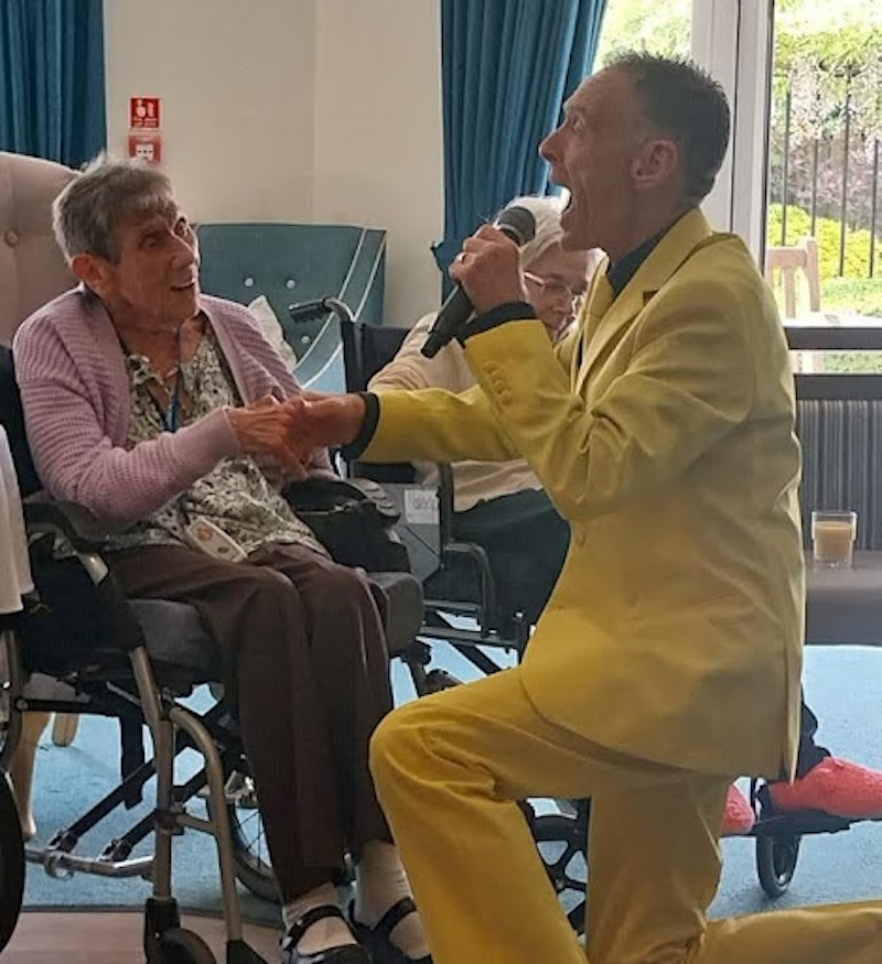 resident kneeling singing holding hands with one of our resident's