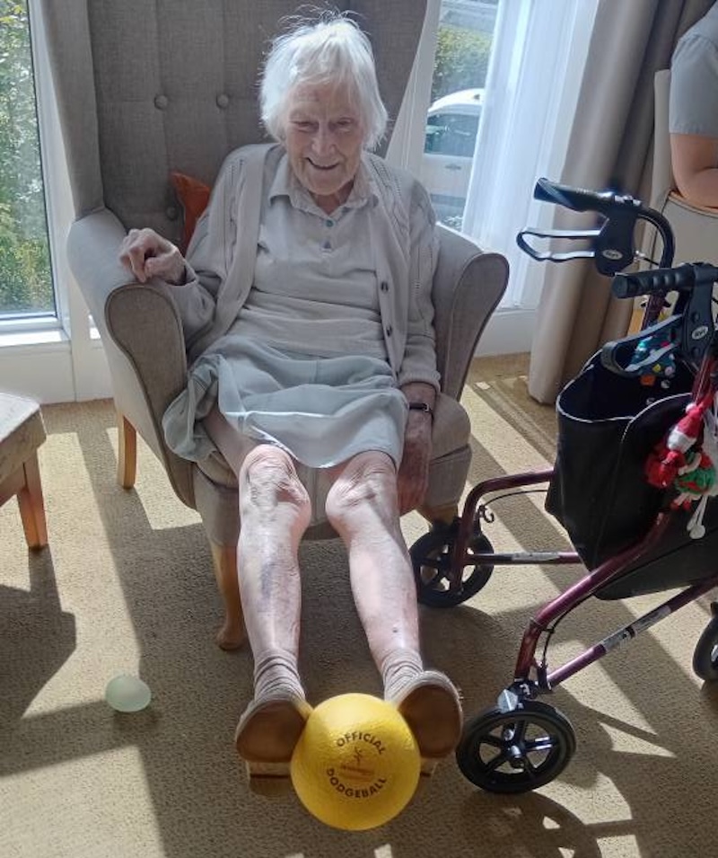 one of our residents sat in an armchair lifting up a yellow ball with her feet