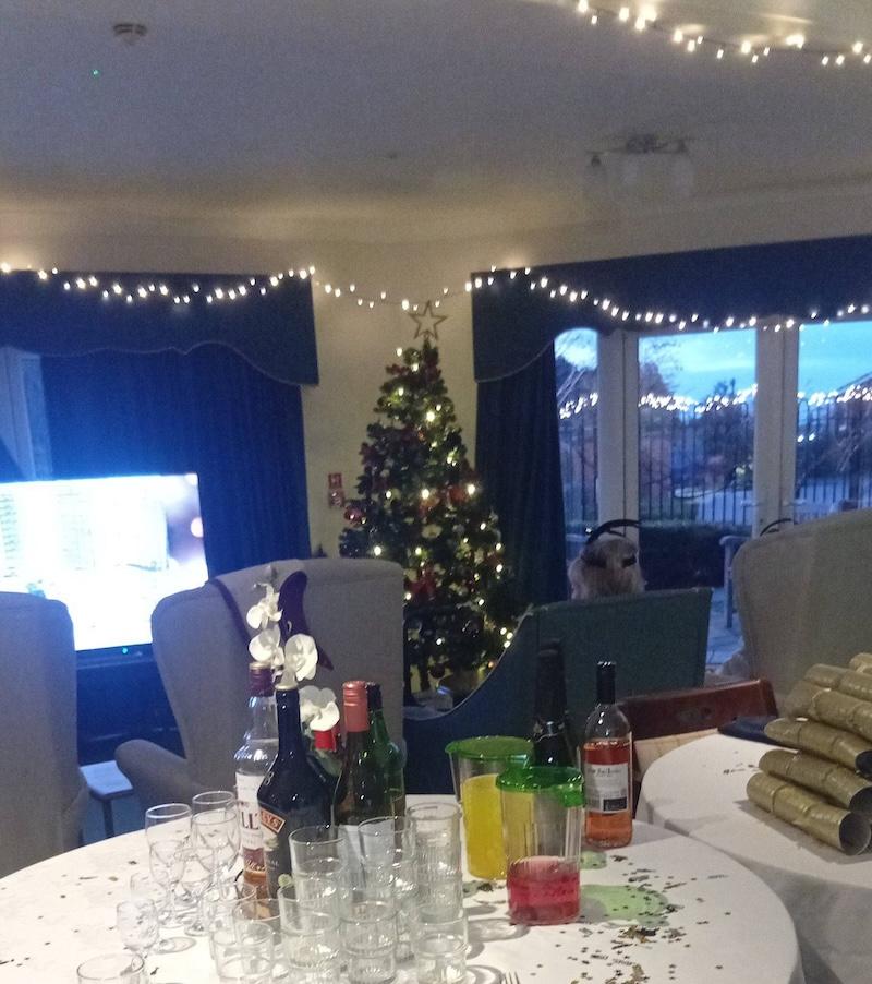 Christmas tree and decorations lighting up a lounge with tables set up with celebratory drinks