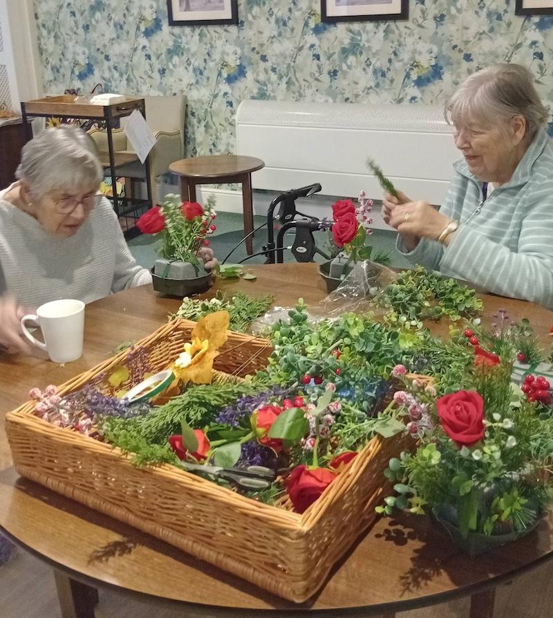 residents sat at a table doing flower arranging