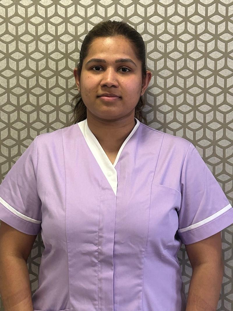 woman with brown hair wearing a lilac care assistant uniform smiling having her photo taken for the team page