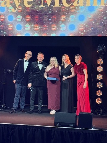 people standing on a stage holding an award