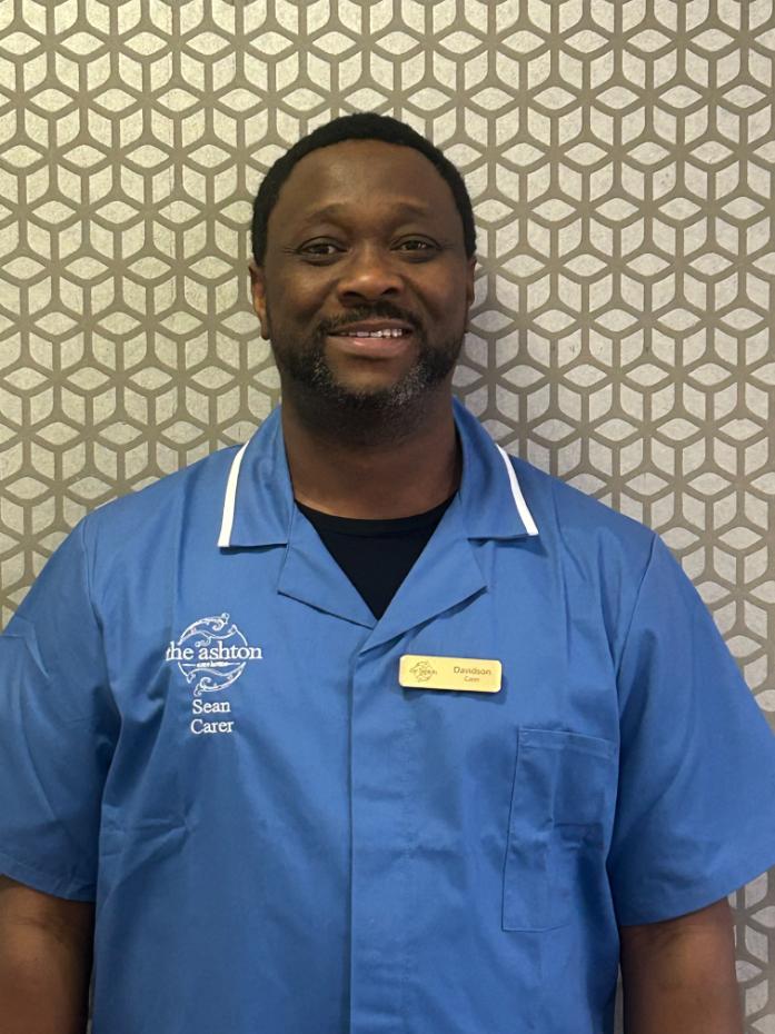 man in blue care uniform smiling for staff photo