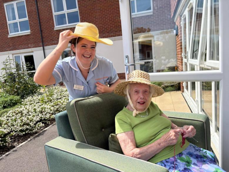 a carer and an older lady wearing hats