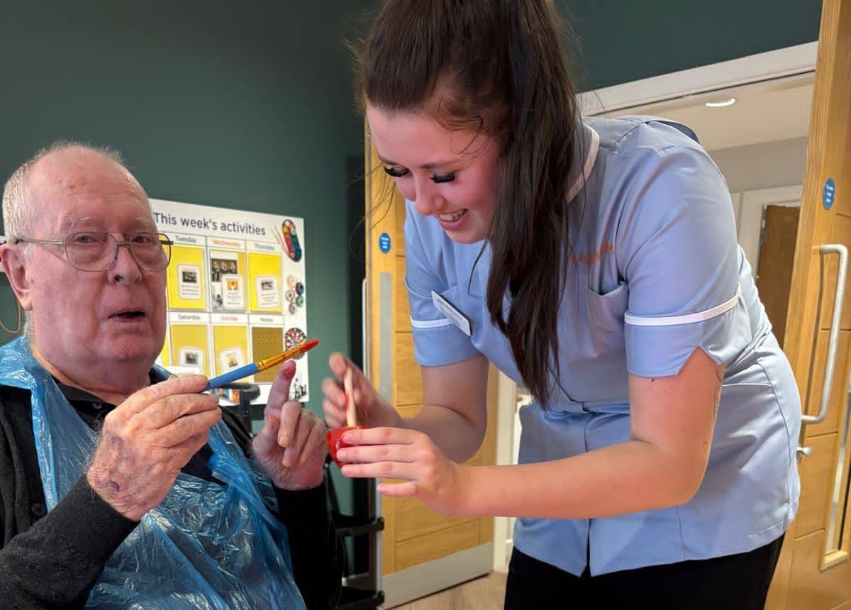 carer and an older man painting