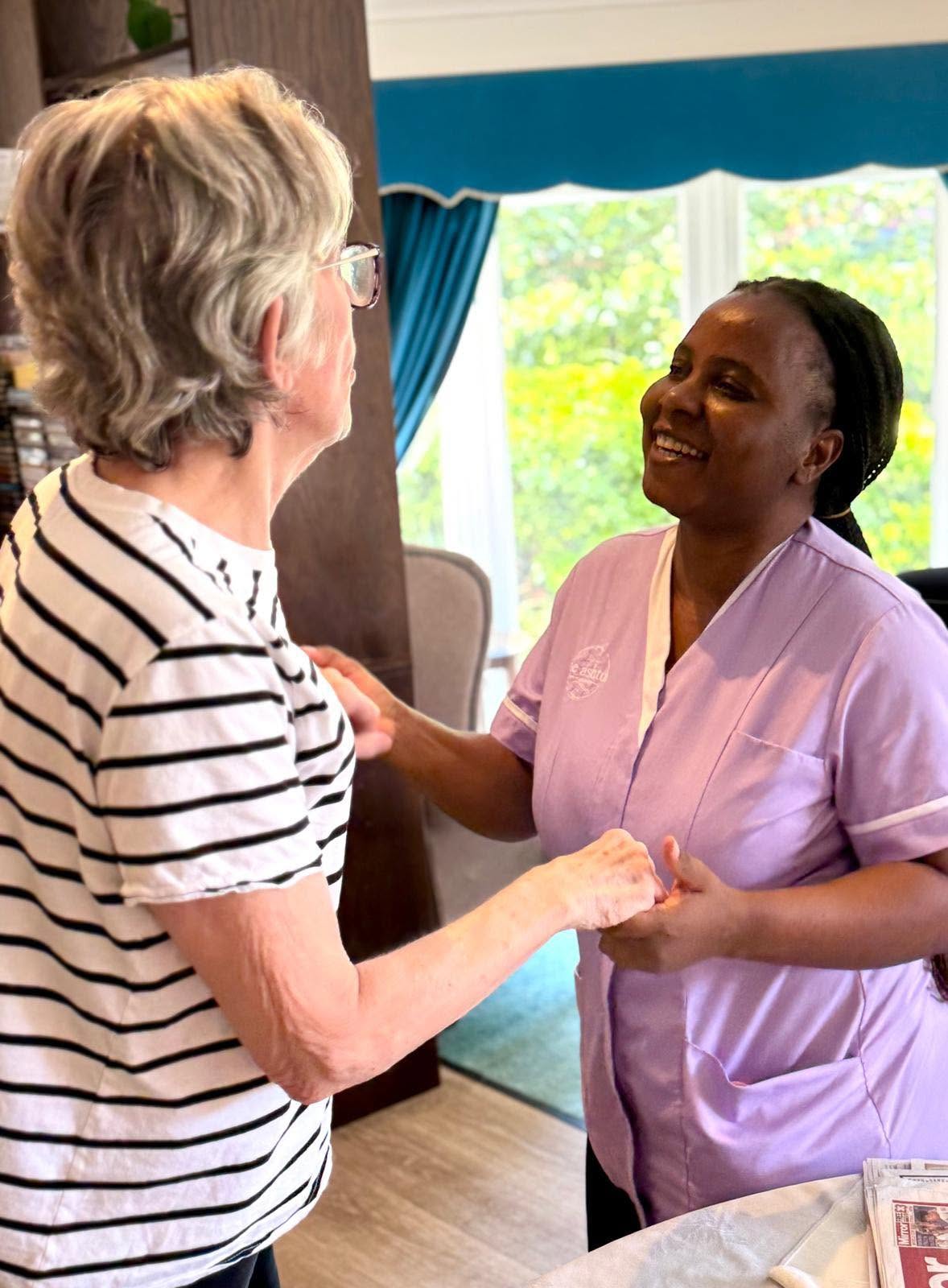 resident and carer smiling holding hands